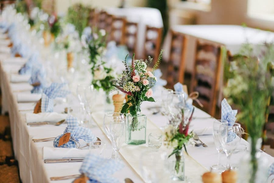 Long reception table with gingham linen and blooms