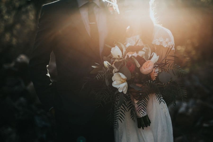 Wedding couple with bouquet in golden evening light